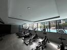 Modern fitness center with exercise equipment and pool view