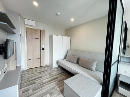 Modern living room with wooden flooring, couch, and storage