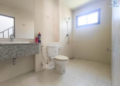 Modern bathroom with white tiles, a shower, toilet, and sink