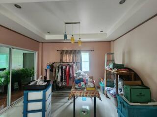 Room with hanging clothes, table, and miscellaneous items