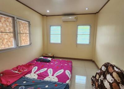 A simple bedroom with a mattress on the floor, air conditioning, and small windows