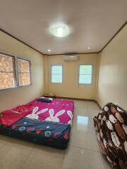 A simple bedroom with a mattress on the floor, air conditioning, and small windows