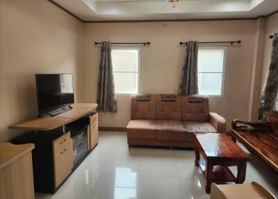 Living room with brown sofa, TV, and wooden furniture