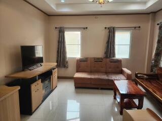 Living room with brown sofa, TV, and wooden furniture