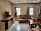 Living room with brown sofa, TV, and wooden furniture