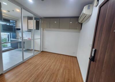 Small living room with wooden flooring, adjacent kitchen