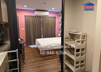 Bedroom with bed, curtains, air conditioner unit, small dining table with chairs, storage unit, and wooden flooring