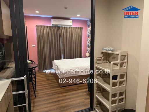 Bedroom with bed, curtains, air conditioner unit, small dining table with chairs, storage unit, and wooden flooring