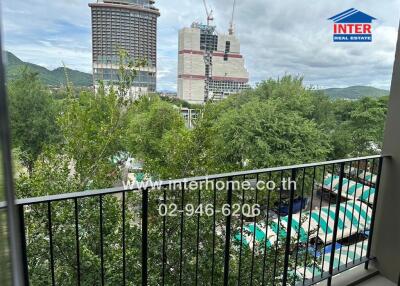 View from balcony showcasing surrounding area including trees and nearby high-rise buildings under construction