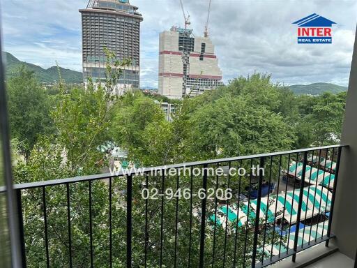 View from balcony showcasing surrounding area including trees and nearby high-rise buildings under construction