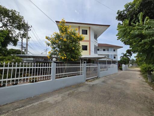 Exterior view of a multi-story residential building with a gated front yard