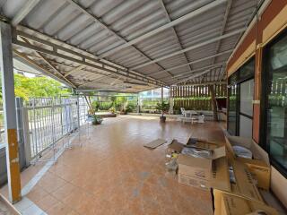 Spacious covered outdoor area with tiled flooring and garden view