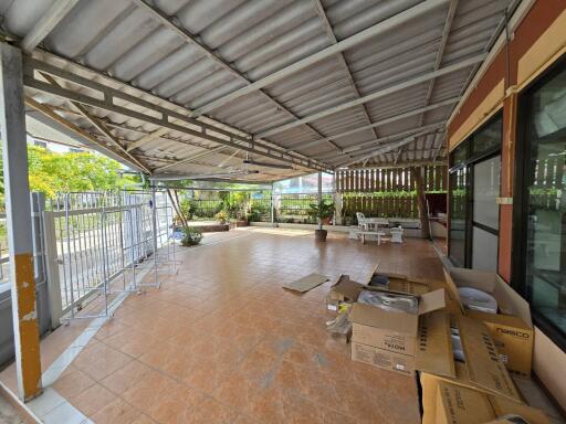 Spacious covered outdoor area with tiled flooring and garden view