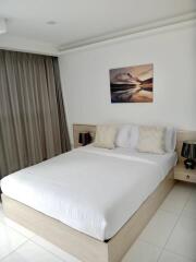 Well-lit bedroom with a large bed, nightstands, and wall art