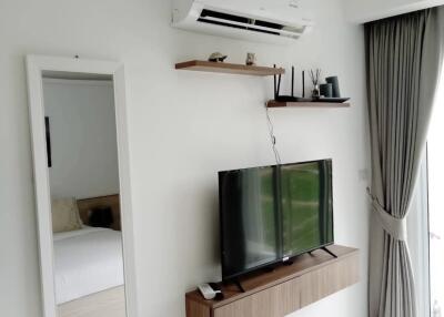 Modern living area with TV, shelving, and air conditioner
