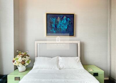 Bedroom with bed, two nightstands, a painting, and a bouquet of flowers