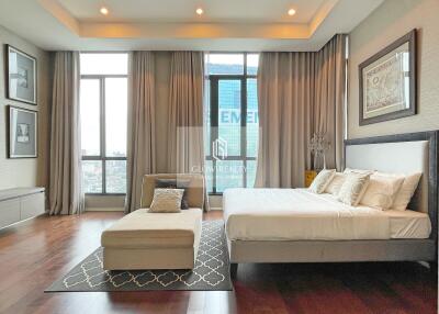 Spacious bedroom with large windows, modern furniture, and a cozy seating area.