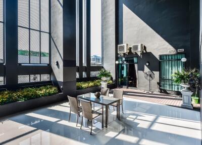 Modern outdoor terrace with table and chairs, potted plants, and tall building