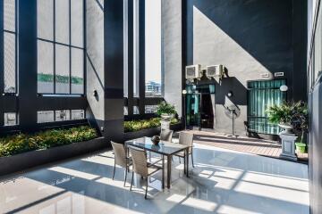 Modern outdoor terrace with table and chairs, potted plants, and tall building