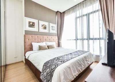 Modern bedroom with a large window, wooden floor, and soft toned decor.