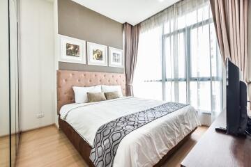 Modern bedroom with a large window, wooden floor, and soft toned decor.