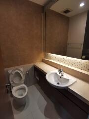 Modern bathroom with toilet, sink, and mirror