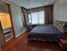 Spacious bedroom with a large bed, wooden flooring, and ample natural light