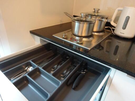 Kitchen with open cutlery drawer and cookware