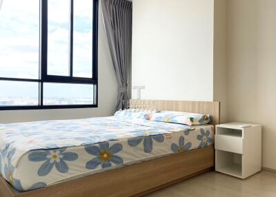 A bright bedroom with large windows and flower-patterned bedding