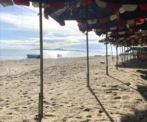 Sunny beach with parasols and boats in the distance