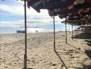 Sunny beach with parasols and boats in the distance