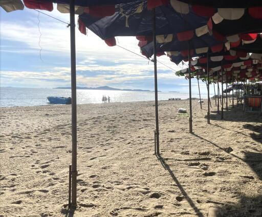 Sunny beach with parasols and boats in the distance