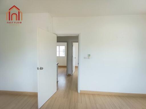 Bright empty bedroom with open door leading to hallway