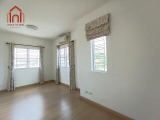 Bright and spacious bedroom with wooden flooring and multiple windows.