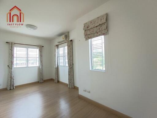 Bright and spacious bedroom with wooden flooring and multiple windows.