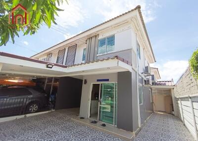 Two-story house exterior with carport and tiled driveway