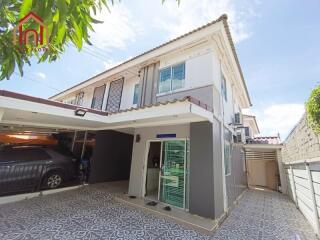 Two-story house exterior with carport and tiled driveway