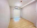 Empty bedroom with wooden flooring and an air conditioner