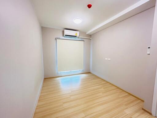 Empty bedroom with wooden flooring and an air conditioner