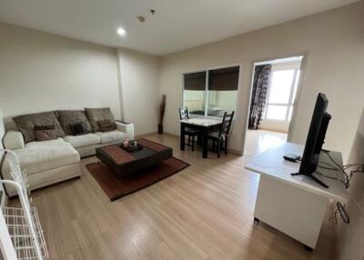 Modern living room with a sofa, coffee table, dining area, and TV