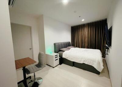 Modern bedroom with bed, desk and chair, and wall-mounted TV