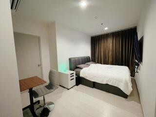 Modern bedroom with bed, desk and chair, and wall-mounted TV