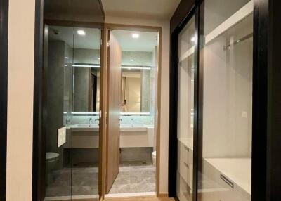 Modern walk-in closet leading to a bathroom with ample storage space