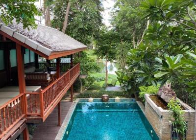 Outdoor area with a swimming pool and a covered wooden patio