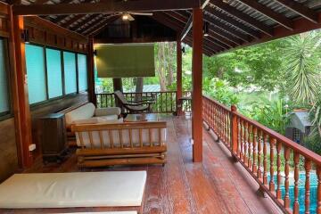 Spacious wooden balcony with outdoor furniture and lush green surroundings