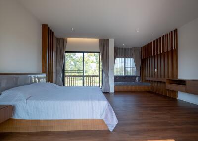 Spacious modern bedroom with wooden floor and large windows