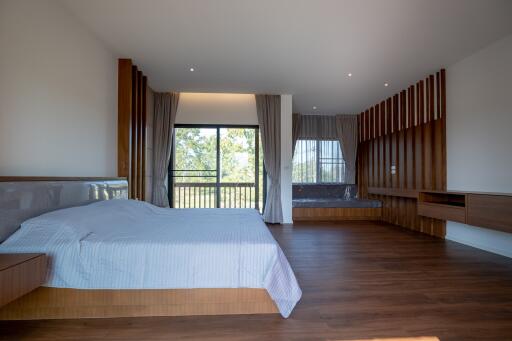 Spacious modern bedroom with wooden floor and large windows