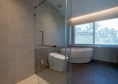 Modern bathroom with glass shower, bathtub, and large window