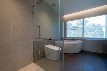 Modern bathroom with glass shower, bathtub, and large window