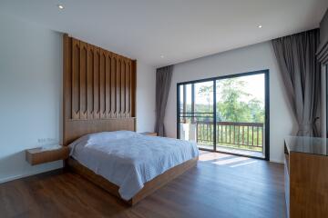 Spacious bedroom with large windows and a wooden accent wall